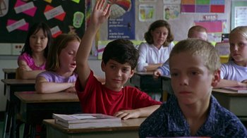 Movie still from “The Station Agent” (2003), directed by Tom McCarthy – A boy raises his hand while sitting at a desk; Medium shot, High angle