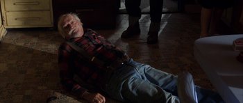 Movie still from “The Straight Story” (1999), directed by David Lynch – An older man laying on the ground in a room; Medium shot, High angle