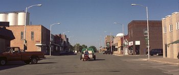 Movie still from “The Straight Story” (1999), directed by David Lynch – A man riding a tractor down a street; Extreme Wide shot, High angle