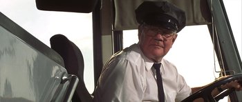 Movie still from “The Straight Story” (1999), directed by David Lynch – An older man wearing a hat sitting in the driver's seat of a bus; Close Up shot, Low angle