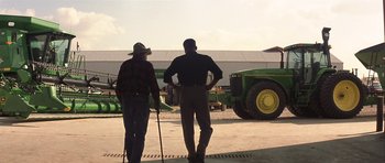 Movie still from “The Straight Story” (1999), directed by David Lynch – Two men are standing in front of a tractor; Wide shot, Over the shoulder angle