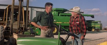 Movie still from “The Straight Story” (1999), directed by David Lynch – Two men standing in front of a john deere tractor; Medium shot, Over the shoulder angle