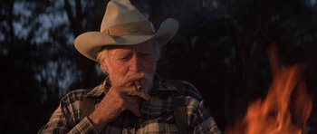 Movie still from “The Straight Story” (1999), directed by David Lynch – An old man wearing a cowboy hat smoking a cigar; Close Up shot, Low angle