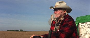 Movie still from “The Straight Story” (1999), directed by David Lynch – An older man wearing a cowboy hat sitting in the driver's seat of a tractor; Medium shot, Over the shoulder angle
