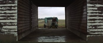 Movie still from “The Straight Story” (1999), directed by David Lynch – A man sitting on top of a lawn mower in an enclosed area; Wide shot, Low angle