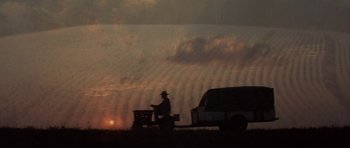 Movie still from “The Straight Story” (1999), directed by David Lynch – A man on a tractor pulling a truck behind it; Extreme Wide shot, Low angle