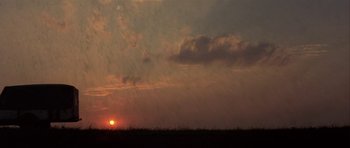 Movie still from “The Straight Story” (1999), directed by David Lynch – The sun is setting over a field of dry grass; Extreme Wide shot, Low angle