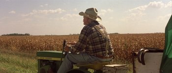 Movie still from “The Straight Story” (1999), directed by David Lynch – An older man sitting on a tractor in a field; Wide shot, Over the shoulder angle