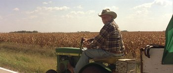 Movie still from “The Straight Story” (1999), directed by David Lynch – An older man sitting on top of a green tractor; Wide shot, Over the shoulder angle