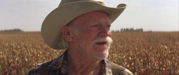 Movie still from “The Straight Story” (1999), directed by David Lynch – An old man with a cowboy hat in a corn field; Close Up shot, Over the shoulder angle