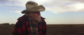 Movie still from “The Straight Story” (1999), directed by David Lynch – An older man wearing a cowboy hat in the middle of a field; Close Up shot, Low angle