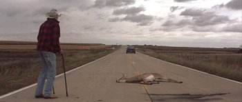 Movie still from “The Straight Story” (1999), directed by David Lynch – A dead antelope laying on the side of a road; Wide shot, High angle