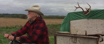 Movie still from “The Straight Story” (1999), directed by David Lynch – An older man wearing a cowboy hat sitting on a bench; Medium shot, Low angle