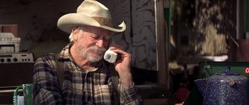 Movie still from “The Straight Story” (1999), directed by David Lynch – An older man wearing a cowboy hat talking on a cell phone; Close Up shot, Low angle