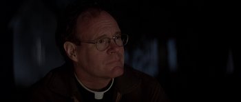 Movie still from “The Straight Story” (1999), directed by David Lynch – A man wearing glasses and a priest's collar; Close Up shot, Low angle