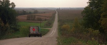Movie still from “The Straight Story” (1999), directed by David Lynch – A truck driving down a dirt road near a field; Extreme Wide shot, High angle