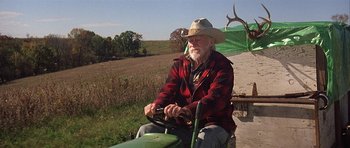 Movie still from “The Straight Story” (1999), directed by David Lynch – An older man sitting on top of a green tractor; Medium shot, Low angle