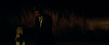 Movie still from “The Strangers” (2008), directed by Bryan Bertino – A man standing in the dark looking at his cell phone; Medium shot, Over the shoulder angle