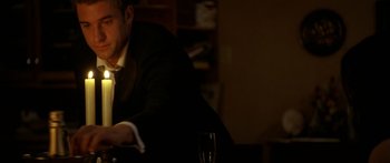 Movie still from “The Strangers” (2008), directed by Bryan Bertino – A man sitting at a table with a glass of wine; Medium shot, High angle