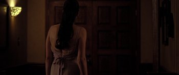 Movie still from “The Strangers” (2008), directed by Bryan Bertino – A woman standing in front of a wooden door; Medium shot, Over the shoulder angle