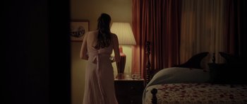 Movie still from “The Strangers” (2008), directed by Bryan Bertino – A woman standing in front of a dresser looking at a lamp; Medium shot, Over the shoulder angle