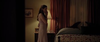 Movie still from “The Strangers” (2008), directed by Bryan Bertino – A woman standing in front of a lamp in a room; Medium shot, High angle