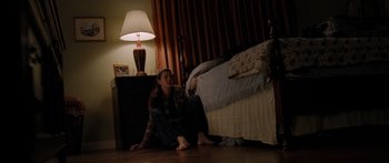 Movie still from “The Strangers” (2008), directed by Bryan Bertino – A woman sitting on the floor in front of a bed; Wide shot, High angle