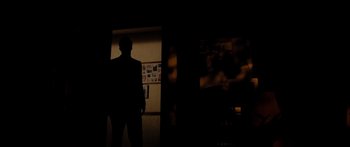 Movie still from “The Strangers” (2008), directed by Bryan Bertino – A man standing in a dark room in front of a wall; Wide shot, Low angle