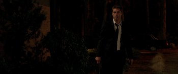 Movie still from “The Strangers” (2008), directed by Bryan Bertino – A man in a suit and tie holding a knife; Medium shot, Over the shoulder angle