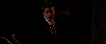 Movie still from “The Strangers” (2008), directed by Bryan Bertino – A man wearing a suit and tie standing in the dark; Medium shot, Over the shoulder angle