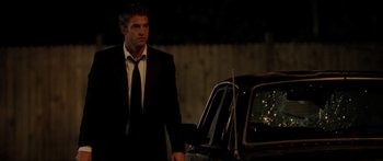 Movie still from “The Strangers” (2008), directed by Bryan Bertino – A man standing next to a car in a suit; Medium shot, Over the shoulder angle