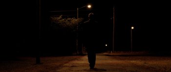 Movie still from “The Strangers” (2008), directed by Bryan Bertino – A man walking down a street at night; Wide shot, Low angle