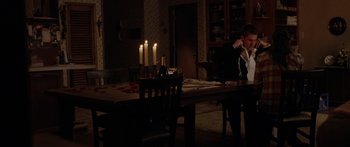 Movie still from “The Strangers” (2008), directed by Bryan Bertino – A man sitting at a dinner table in the dark; Wide shot, High angle