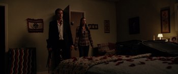 Movie still from “The Strangers” (2008), directed by Bryan Bertino – A man and a woman standing next to each other in front of a bed; Wide shot, Over the shoulder angle
