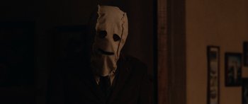 Movie still from “The Strangers” (2008), directed by Bryan Bertino – A person wearing a mask and a suit; Close Up shot, Over the shoulder angle