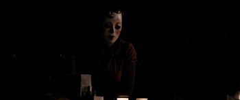 Movie still from “The Strangers” (2008), directed by Bryan Bertino – A woman wearing a mask in a dark room; Medium shot, Low angle