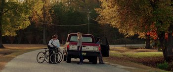 Movie still from “The Strangers” (2008), directed by Bryan Bertino – A group of people standing next to a red pick up truck; Wide shot, High angle