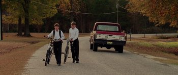 Movie still from “The Strangers” (2008), directed by Bryan Bertino – Two young men walking down the street with their bikes; Wide shot, High angle