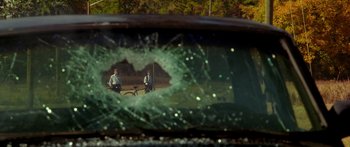 Movie still from “The Strangers” (2008), directed by Bryan Bertino – Two people are seen through a broken windshield; Extreme Wide shot, Over the shoulder angle