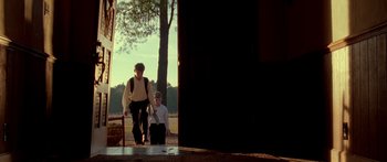 Movie still from “The Strangers” (2008), directed by Bryan Bertino – Two people are walking in a park near a tree; Wide shot, Low angle