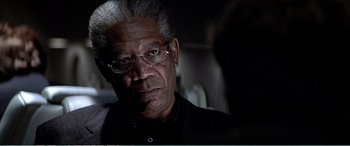 Movie still from “The Sum of All Fears” (2002), directed by Phil Alden Robinson – An older man wearing glasses and a black shirt; Close Up shot, Over the shoulder angle