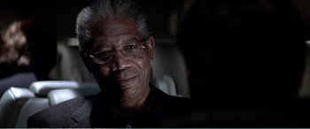 Movie still from “The Sum of All Fears” (2002), directed by Phil Alden Robinson – An older man wearing glasses and a black shirt; Close Up shot, Over the shoulder angle