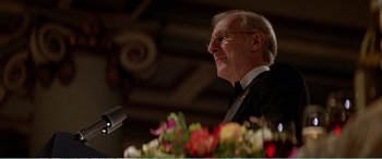Movie still from “The Sum of All Fears” (2002), directed by Phil Alden Robinson – An older man in a suit is speaking at a podium; Close Up shot, Low angle
