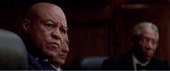 Movie still from “The Sum of All Fears” (2002), directed by Phil Alden Robinson – A man with a shaved head and a bald head is sitting next to another man with a shaved head; Close Up shot, Low angle