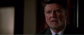 Movie still from “The Sum of All Fears” (2002), directed by Phil Alden Robinson – An older man wearing a suit and tie looking at the camera; Close Up shot, Over the shoulder angle