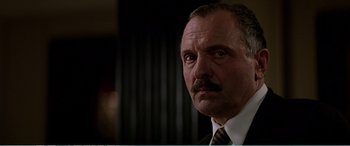 Movie still from “The Sum of All Fears” (2002), directed by Phil Alden Robinson – An older man in a suit and tie looking to his left; Close Up shot, Low angle