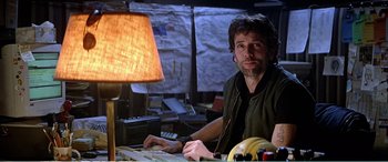 Movie still from “The Sum of All Fears” (2002), directed by Phil Alden Robinson – A man sitting in front of a lamp in a room; Medium shot, Low angle