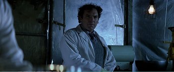 Movie still from “The Sum of All Fears” (2002), directed by Phil Alden Robinson – A man in a white lab coat standing in front of a window; Medium shot, Low angle