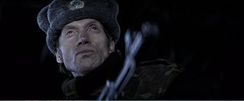 Movie still from “The Sum of All Fears” (2002), directed by Phil Alden Robinson – A person wearing a hat and holding a rifle; Close Up shot, Low angle