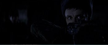 Movie still from “The Sum of All Fears” (2002), directed by Phil Alden Robinson – A man with a camera in the dark looking at the camera; Close Up shot, Over the shoulder angle